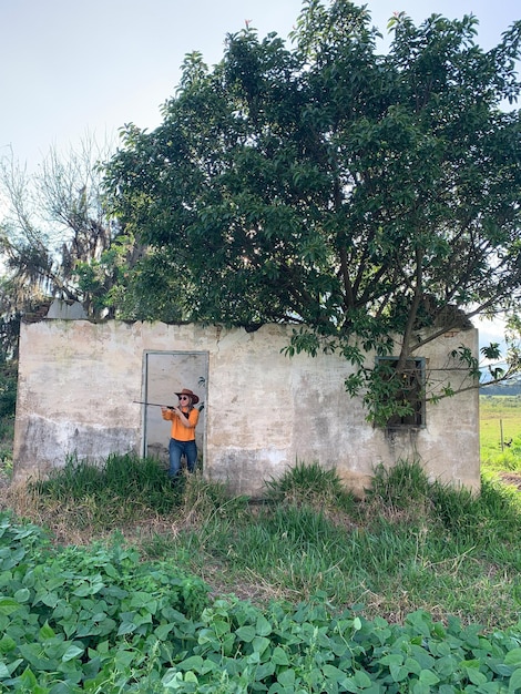 Brazilian blonde woman holding a shotgun in an abandoned house in brazil Orange shirt and hat