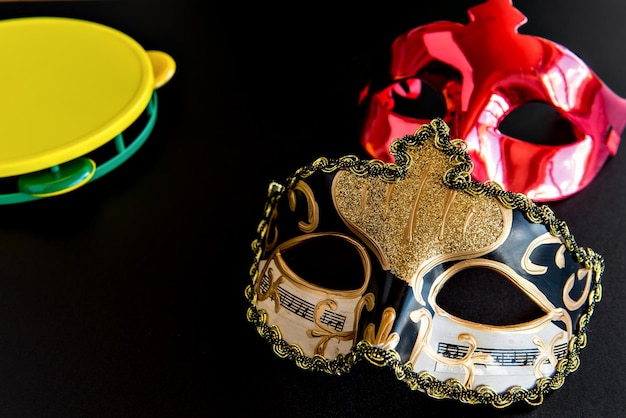 Brazilian carnival concept, carnival mask and tambourine on black background