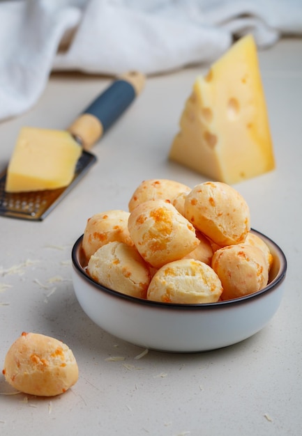 Brazilian cheese bread Freshly baked homemade cheese buns in a white plate on a light background A gourmet snack Delicious pastries Selective focus