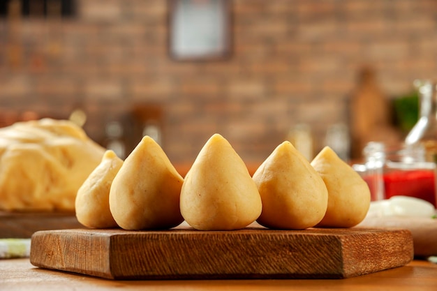 Brazilian chiken croquette coxinha de frango on a wooden table and a bricks kitchen background