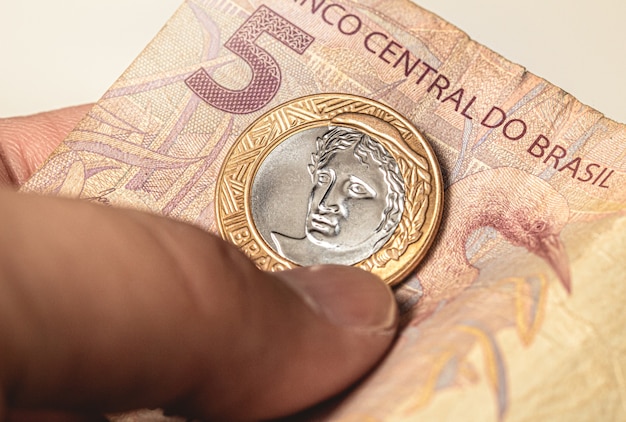 a brazilian coin on a brazilian banknote of five reais in close up photo