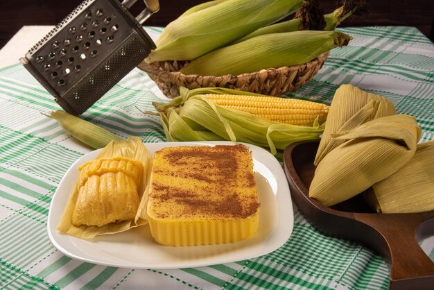 Brazilian Cural candy corn and pamonha corn on the cob arranged on a table with a green and white tablecloth dark background selective focus