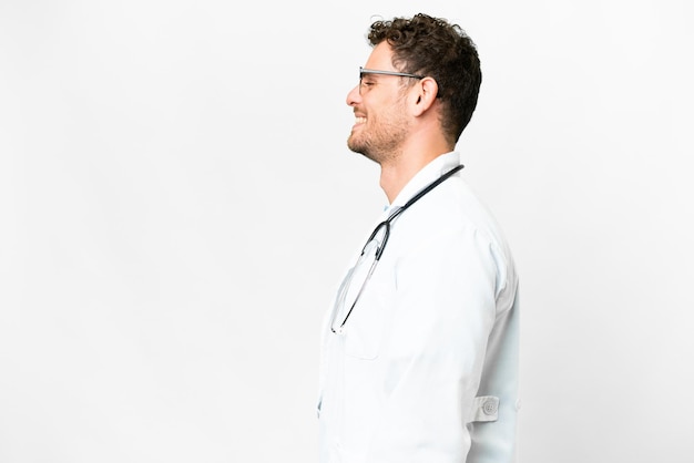 Brazilian doctor man over isolated white background laughing in lateral position