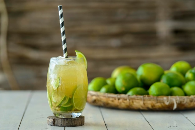 Brazilian drink Caipirinha on a white wooden table with lemons in the background