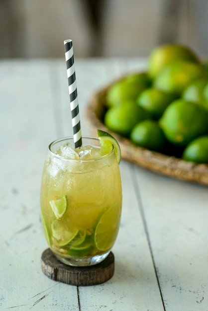 Brazilian drink Caipirinha on a white wooden table with lemons in the background