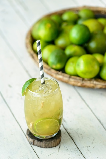 Brazilian drink Caipirinha on a white wooden table with lemons in the background