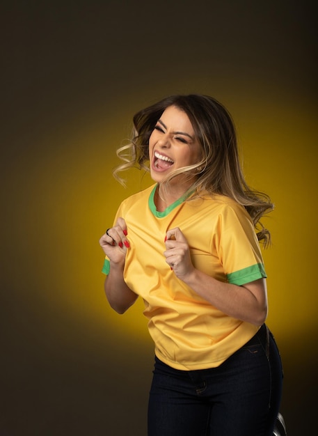 Brazilian fan Brazilian woman fan celebrating in soccer or soccer match on yellow background Brazil colors