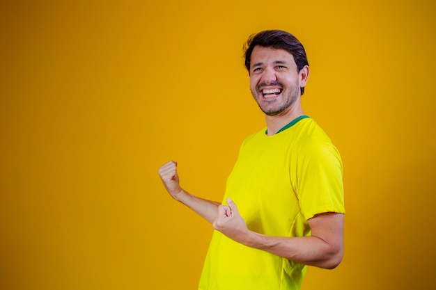 Brazilian fan celebrating on yellow background. Yes!