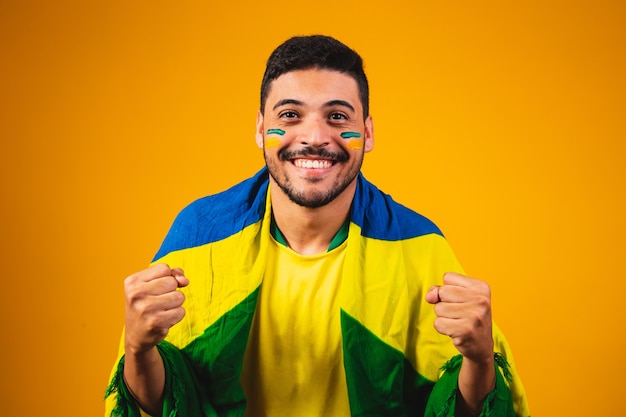 Brazilian fan cheering in the crowd on yellow background.