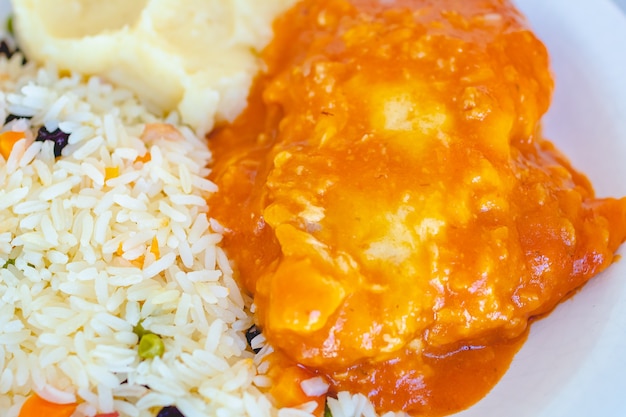 brazilian food chicken parmigiana with greek rice and mashed potatoes on a white plate