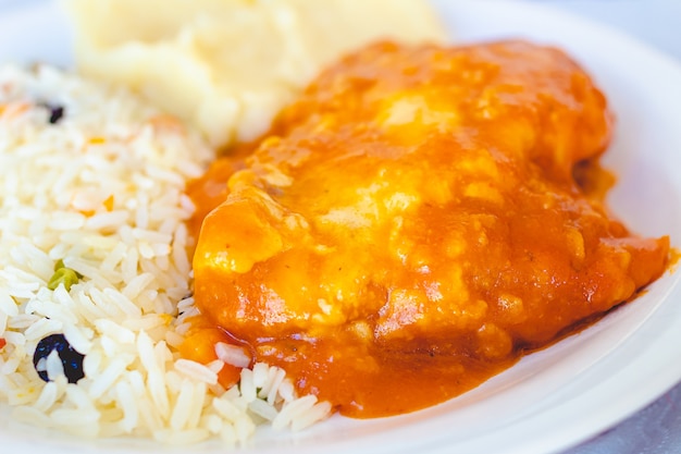 brazilian food chicken parmigiana with greek rice and mashed potatoes on a white plate