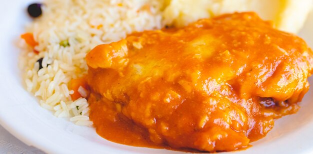 brazilian food chicken parmigiana with greek rice and mashed potatoes on a white plate