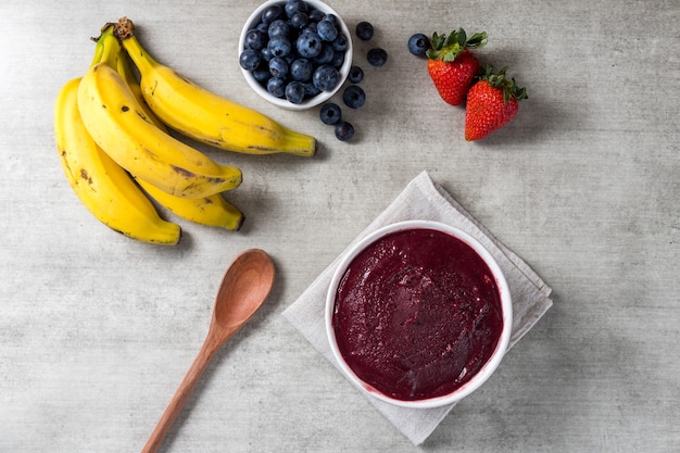 Brazilian frozen and acai berry ice cream bowl. with fruits on wooden background. Summer menu top view. close up.