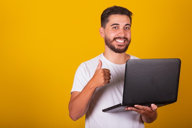 Brazilian Latin American man happy holding notebook and smiling with thumb up concept of work approval optimism technology internet access