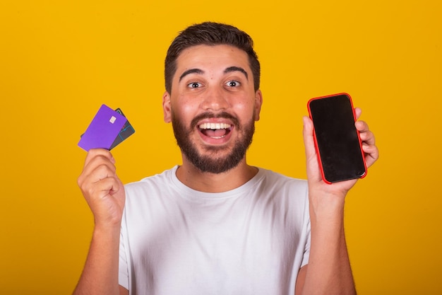 Brazilian Latin American man Surprised and happy showing cellphone screen and credit card mobile phone shopping app internet shopping concept