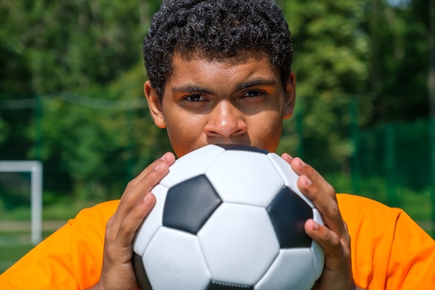 Brazilian man holds soccer ball close up while standing on sports court