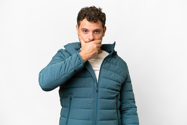 Brazilian man over isolated white background covering mouth with hand