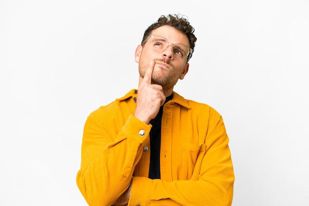 Photo brazilian man over isolated white background having doubts while looking up