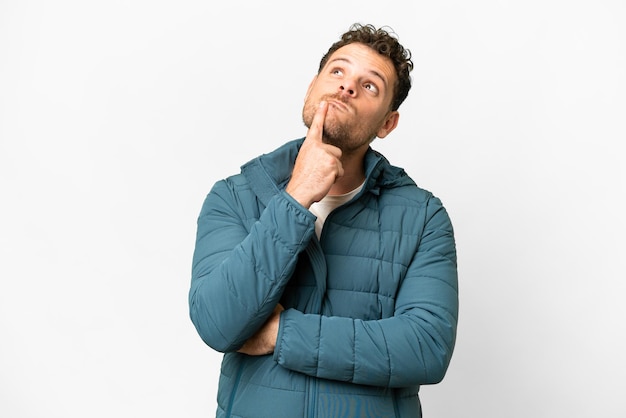 Brazilian man over isolated white background having doubts while looking up