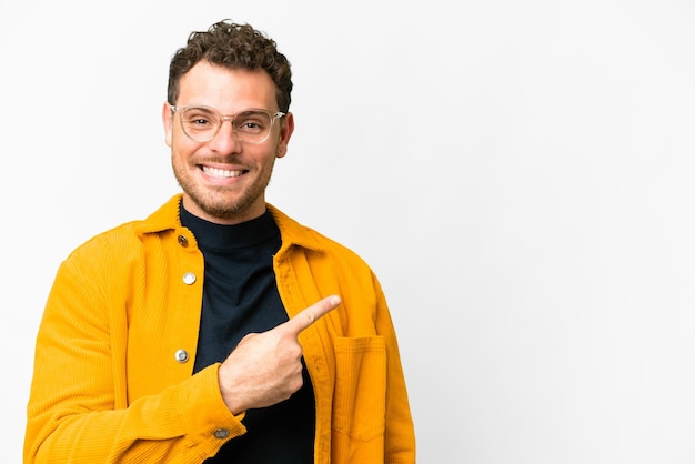 Brazilian man over isolated white background pointing to the side to present a product