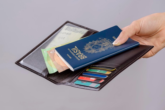 Brazilian passport in a hand with wallet credit cards and euro banknotes on a white background