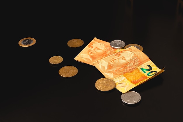 Brazilian real banknotes and coins on a dark table