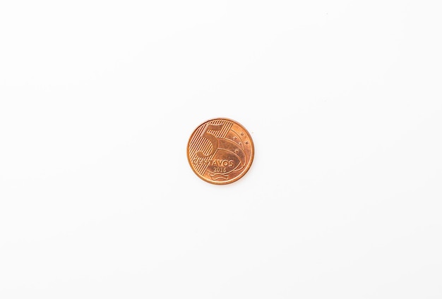 A Brazilian Real five cent coin on a white surface