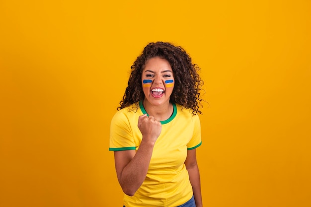 Brazilian supporter Brazilian woman fan celebrating on soccer or football match on yellow background Brazil colors