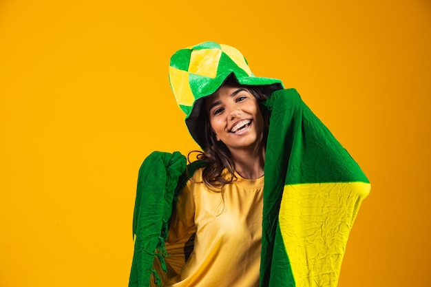 Brazilian supporter. Brazilian woman fan celebrating on soccer or football match on yellow background. Brazil colors.