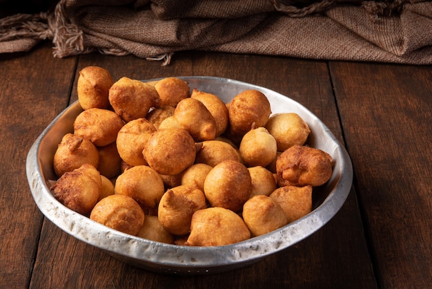 Brazilian sweet called bolinho de Chuva, placed in an aluminum bowl on rustic wood, selective focus.