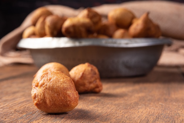 Brazilian sweet called bolinho de Chuva, placed in an aluminum bowl on rustic wood, selective focus.