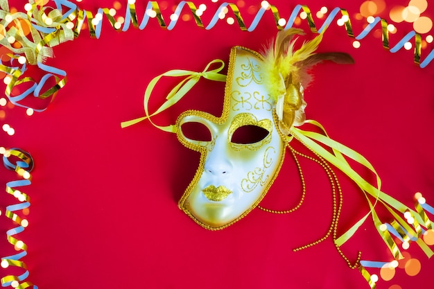 Brazilian or Venetian carnival A bright mask on a red background with a Golden serpentine