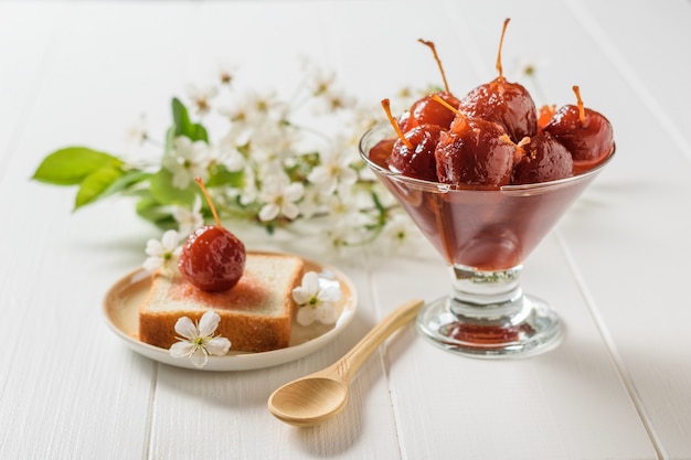 Bread, Apple jam and a sprig of flowers on a wooden table.