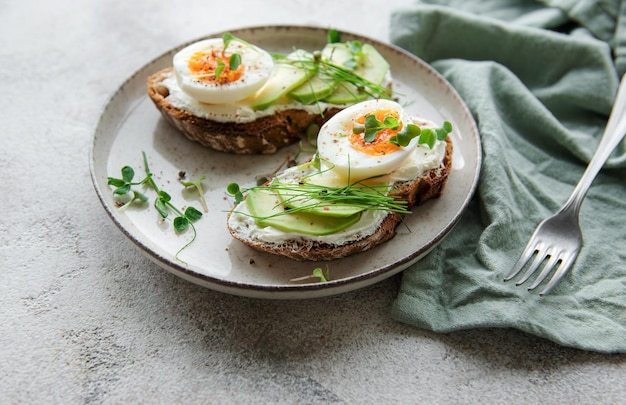 Bread toast boiled eggs avocado slice microgreens on a plate