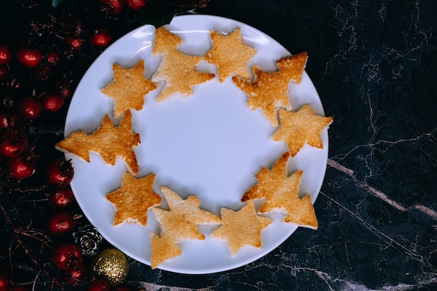 Bread toast in the shape of a Christmas tree and stars lie on a white plate, close-up.Selective focus.