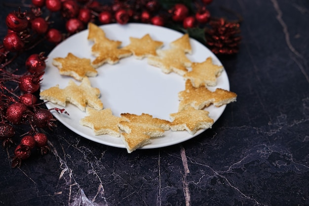 Bread toast in the shape of a Christmas tree and stars lie on a white plate, close-up.Selective focus.