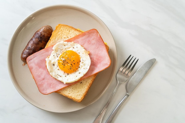 Bread toasted cheese topped ham and fried egg with pork sausage