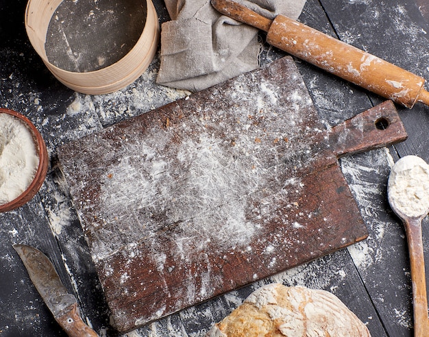 Bread, white wheat flour, wooden rolling pin and old cutting board 