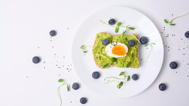 Bread with avocado vegetables fruit and egg on white background Healthy breakfast concept