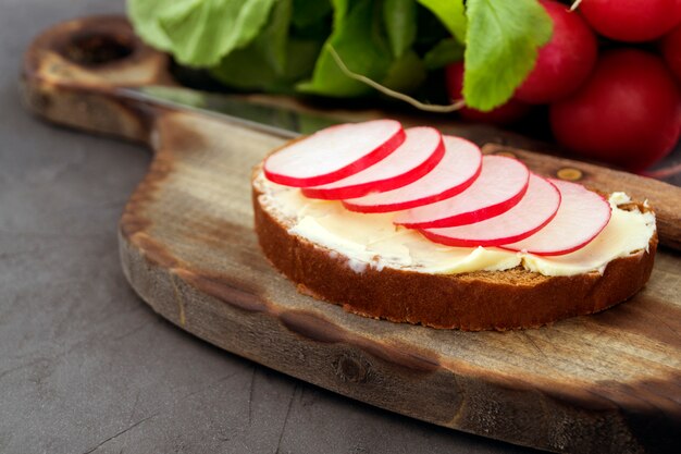 Bread with butter and radish on a wooden Board.