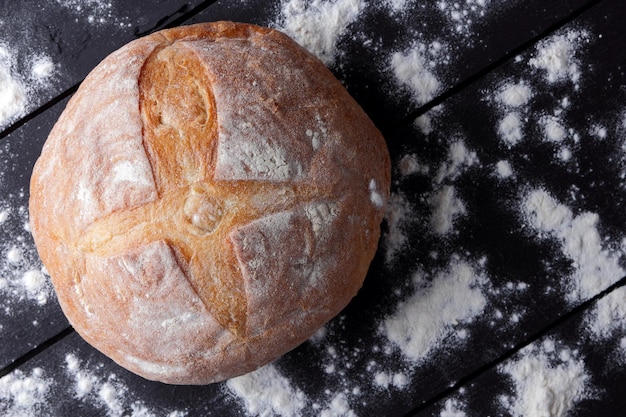 Bread with flour on dark background Wheat bread from oven on dark boards Top view Copy space