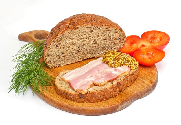 Bread with ham mustard dill and tomato on the wood plate