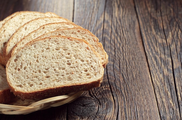 Bread with wheat bran in wicker plate on rustic wooden table