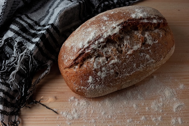 Bread on a wooden table is sprinkled with flour