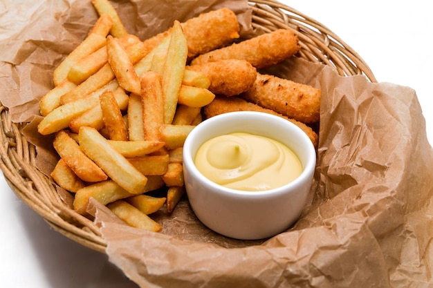 Breaded cheddar cheese sticks with french fries and sauce Served in a wicker basket on craft paper