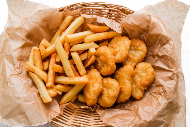 Breaded chicken fillet and french fries Served in a wicker basket on craft paper