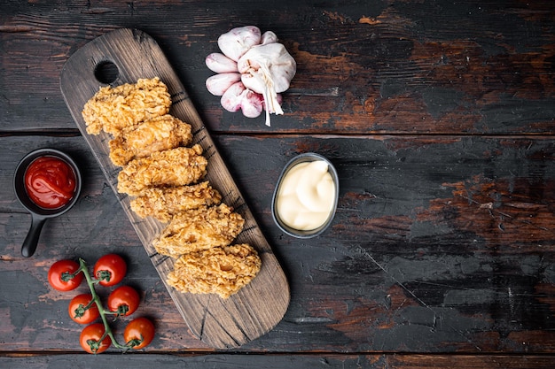 Breaded chicken wings on dark wooden background top view with space for text