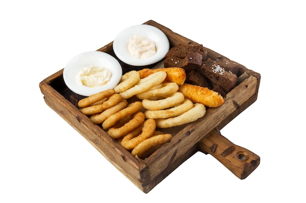 Breaded onion and squid rings crispy croutons and fried cheese with sauce served on a wooden board Appetizing popular snack for beer Closeup Isolated on white background