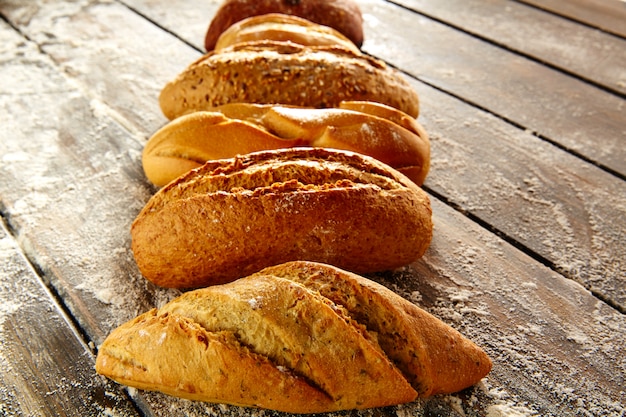 Breads varied in a row on rustic wood and flour