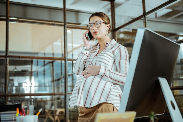 Break from work. Beautiful mature pregnant woman calling her husband during break from work